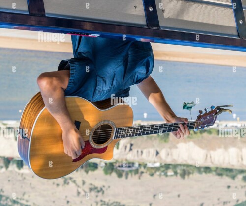 man playing guitar upside down behind his head GP2YEA