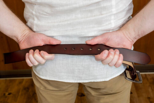 A strict father with a belt in his hands is waiting for his child to scold him severely for educational purposes